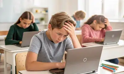 Students looking stressed while using laptops in classroom