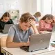 Students looking stressed while using laptops in classroom