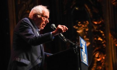 Elderly man speaking at podium during rally