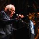 Elderly man speaking at podium during rally