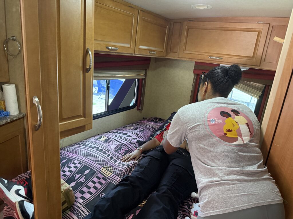 Woman comforting person lying on RV bed