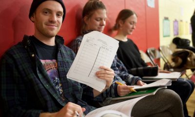 Student holding paper while sitting in classroom hallway