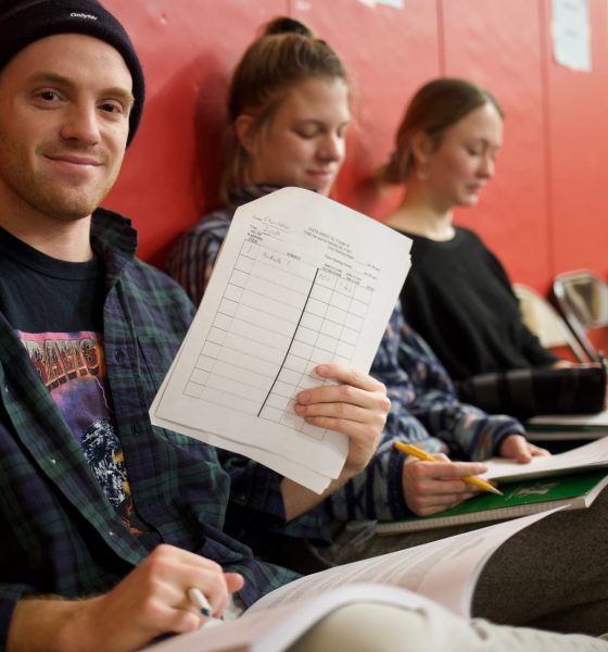 Student holding paper while sitting in classroom hallway