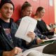 Student holding paper while sitting in classroom hallway
