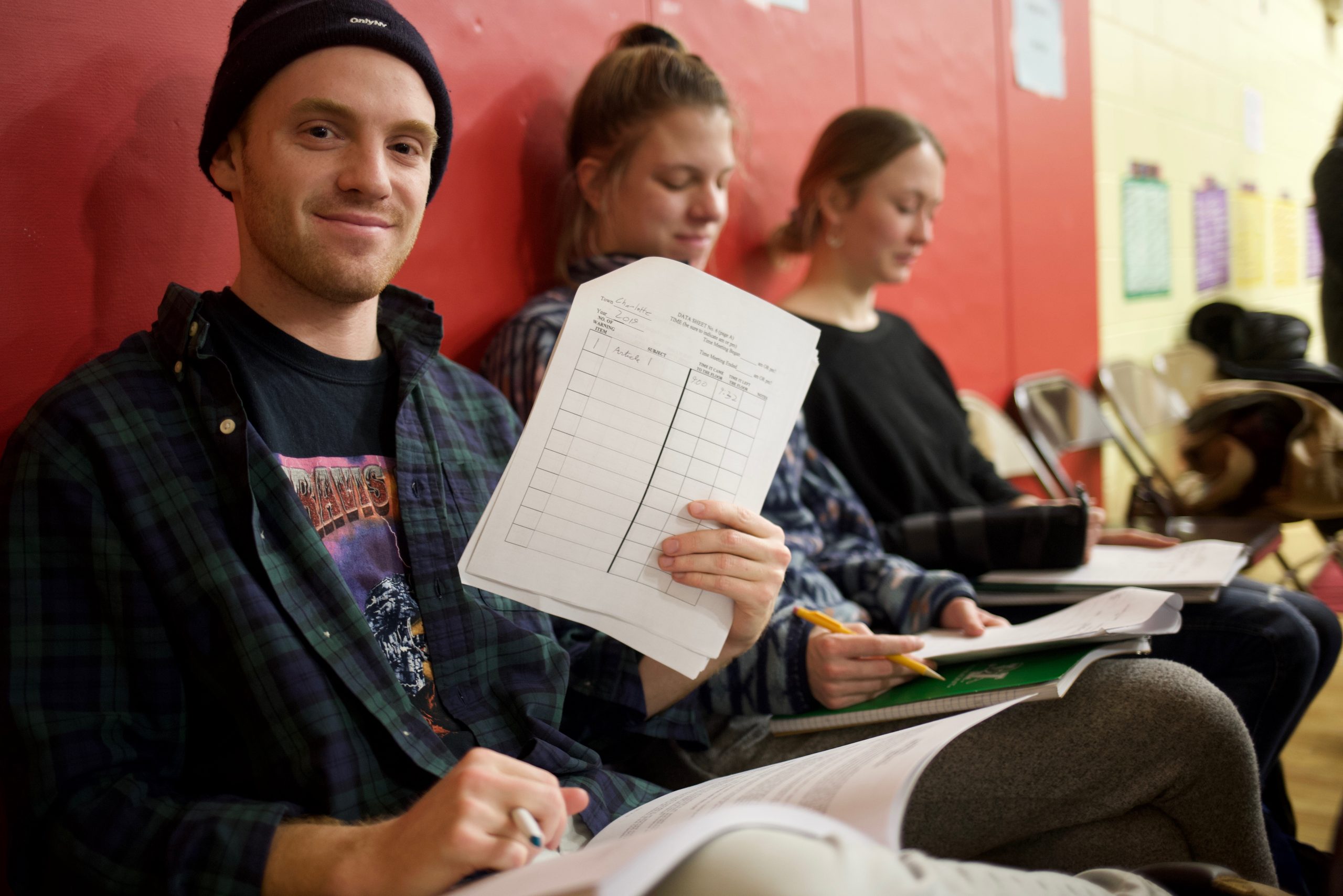 Student holding paper while sitting in classroom hallway