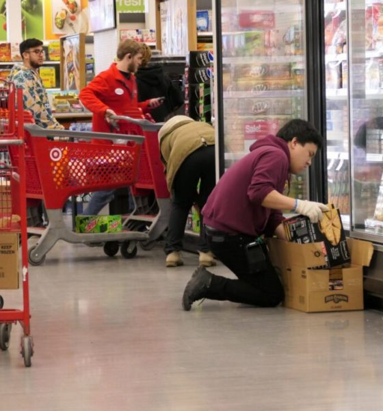 Employee stocking frozen food in grocery store aisle