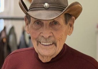 Elderly man in cowboy hat smiling indoors