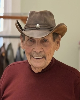 Elderly man in cowboy hat smiling indoors