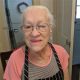 Elderly woman wearing glasses and apron indoors