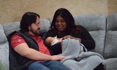 Parents holding newborn baby on couch