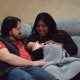 Parents holding newborn baby on couch
