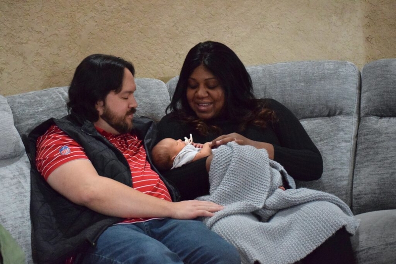 Parents holding newborn baby on couch