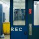 Jail corridor with blue doors and yellow cart