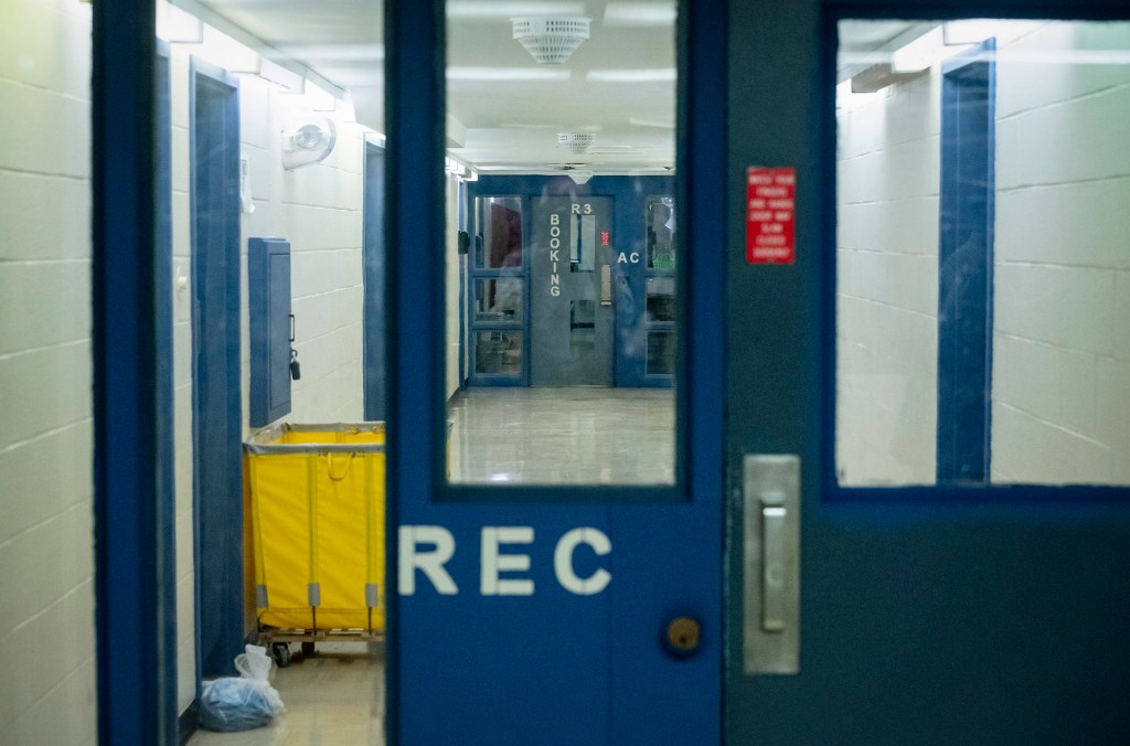 Jail corridor with blue doors and yellow cart