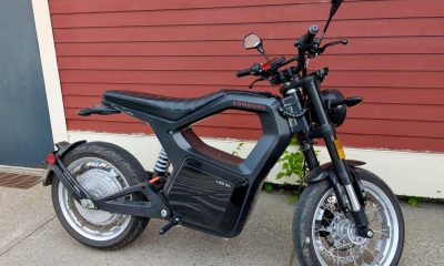 Black SONDORS electric motorcycle parked by red wall
