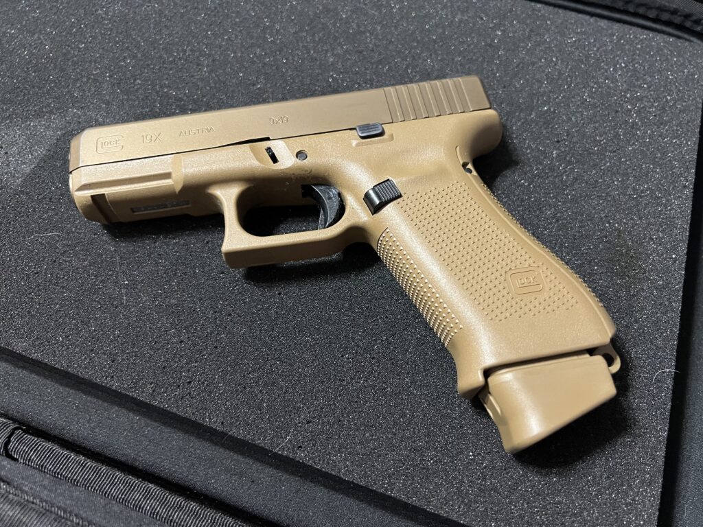 Tan Glock 19X handgun on black surface