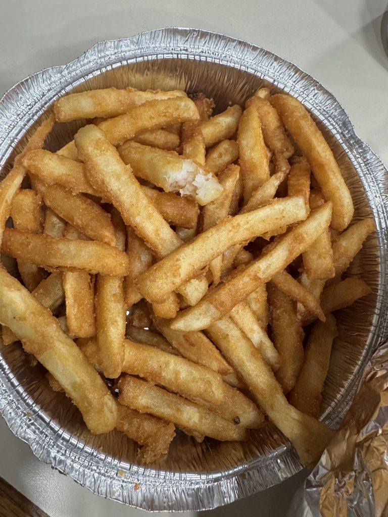Golden French fries in foil takeout container