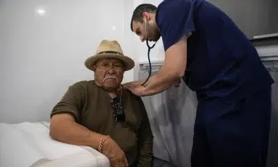 Doctor examining elderly man with stethoscope