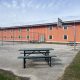 Fenced outdoor yard with picnic tables and basketball hoop