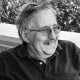 Older man with glasses smiling outdoors