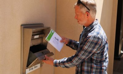 Man placing envelope into ballot drop box