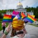 Person wearing Pride flags before capitol building