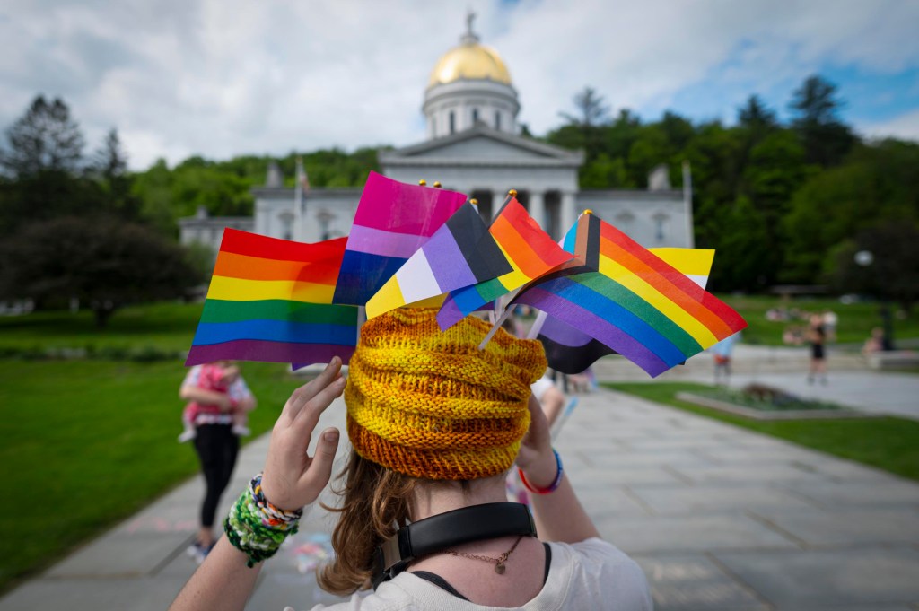 Person wearing Pride flags before capitol building