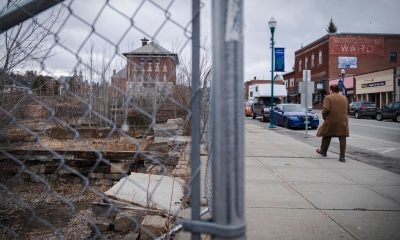 Man walking past fenced vacant lot downtown