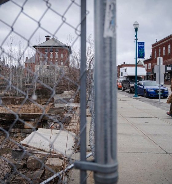 Man walking past fenced vacant lot downtown