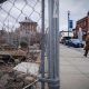 Man walking past fenced vacant lot downtown