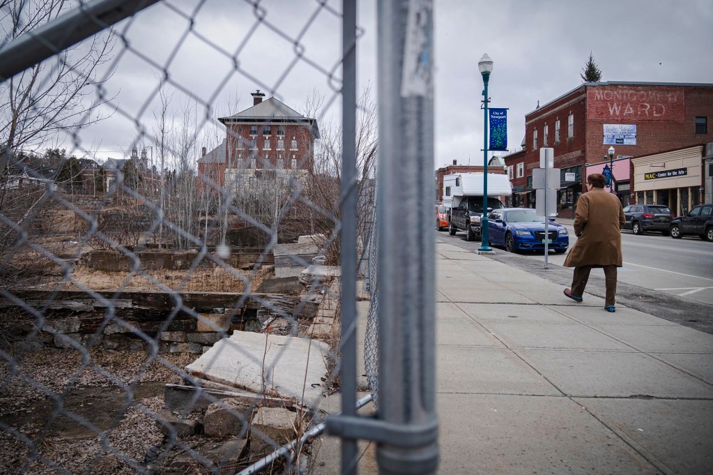 Man walking past fenced vacant lot downtown