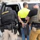 State police arresting man beside patrol vehicle