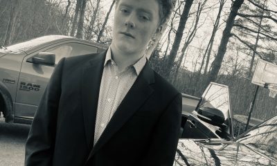 Young man in suit beside parked cars outdoors