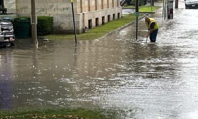 Worker clearing drain in flooded city street