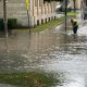 Worker clearing drain in flooded city street
