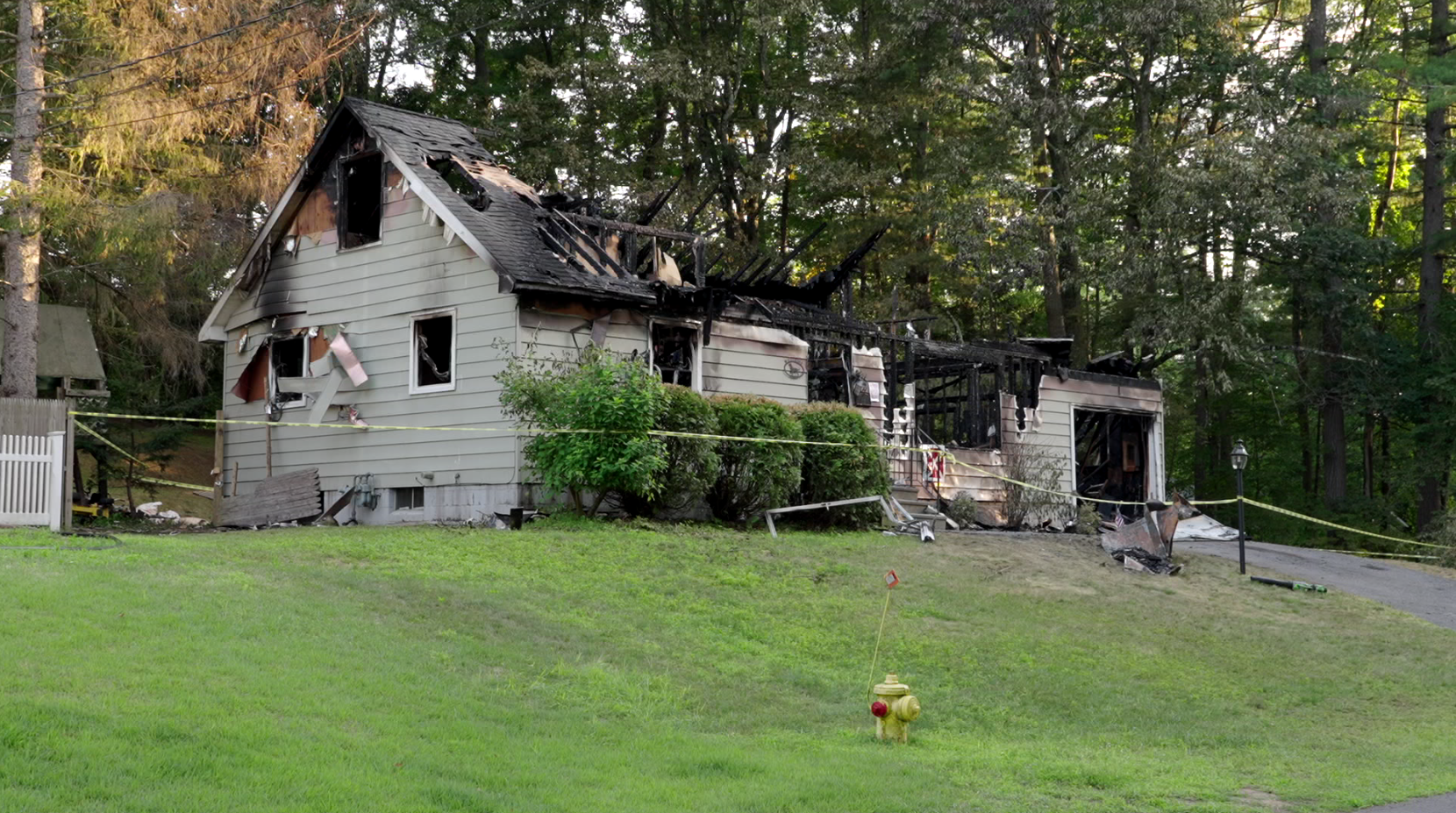 Fire-damaged house with caution tape and charred roof