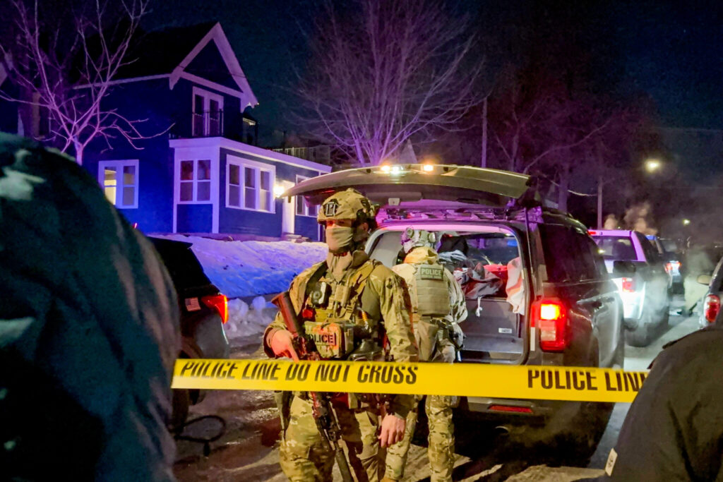 Armed police officers behind crime scene tape at night