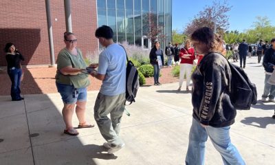 People exchanging flyer outside campus building