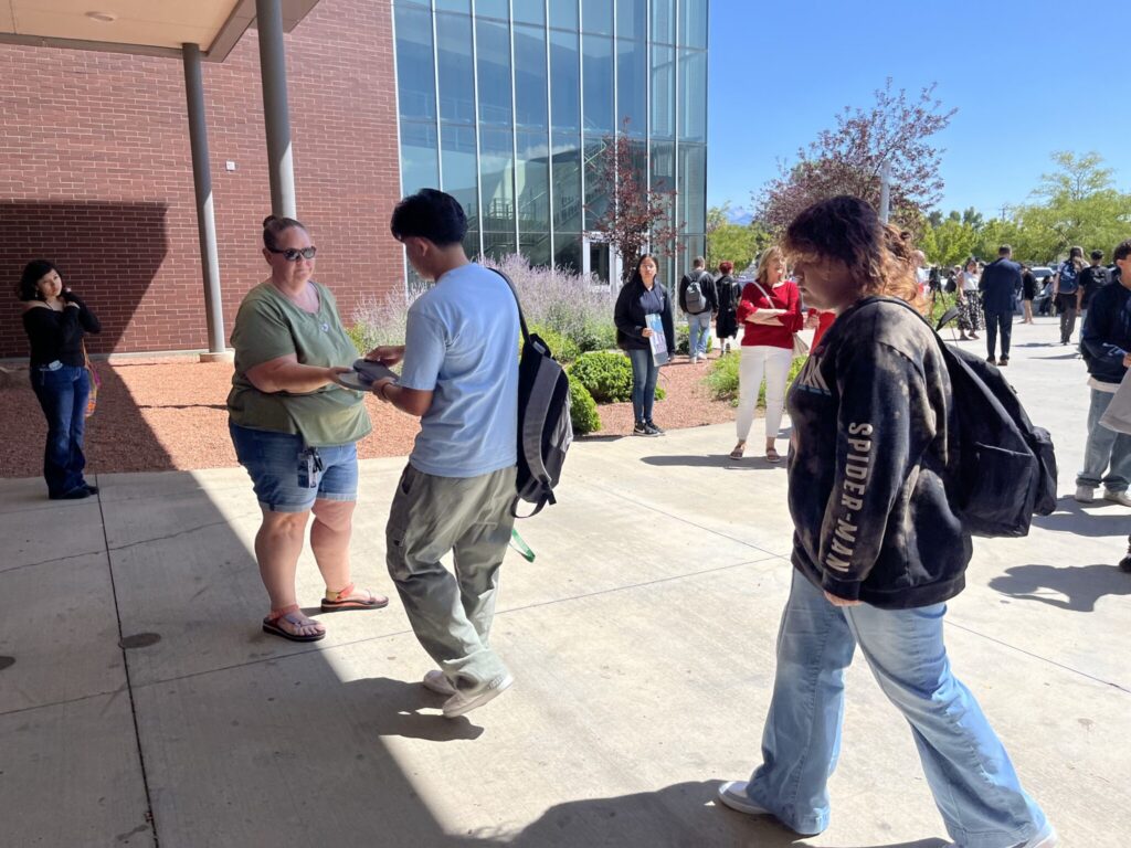 People exchanging flyer outside campus building