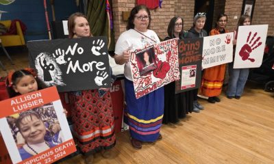 Women holding MMIW protest signs indoors