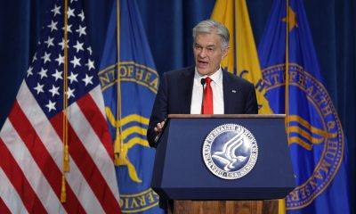 Man speaking at podium with U.S. flags