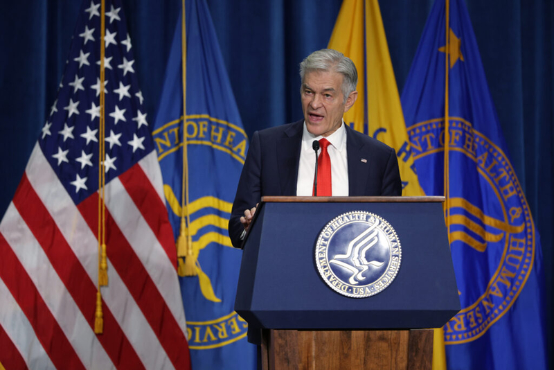 Man speaking at podium with U.S. flags
