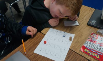 Children playing educational board game at classroom desk