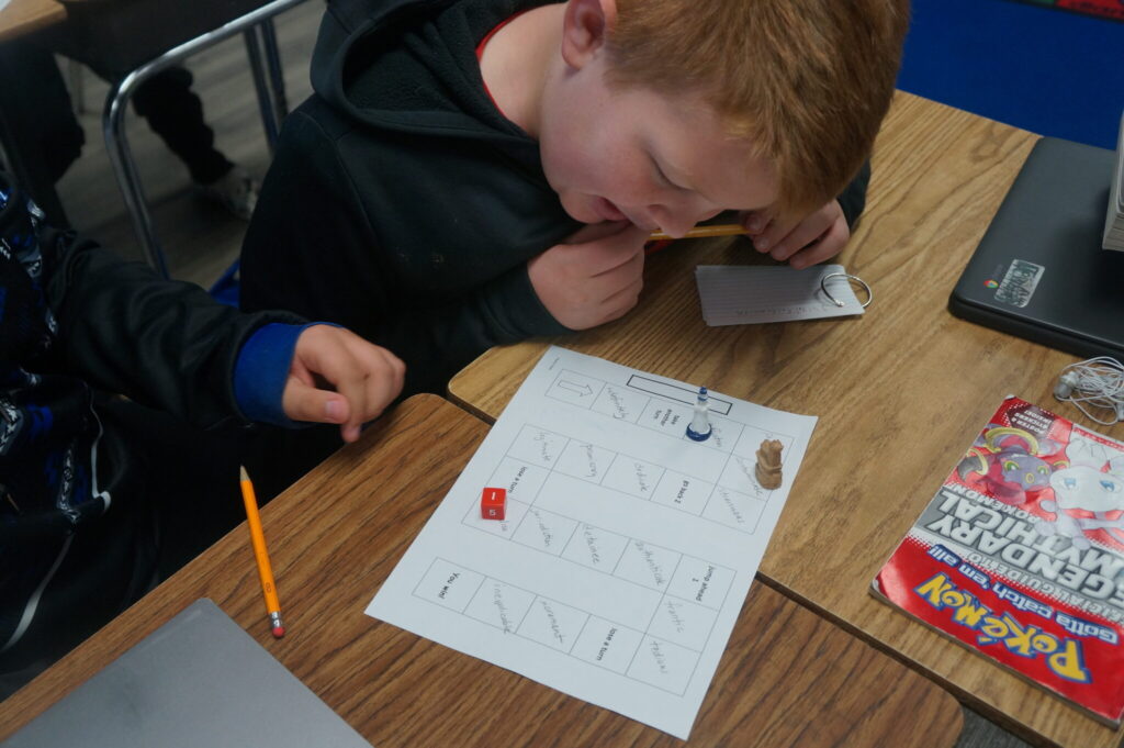 Children playing educational board game at classroom desk