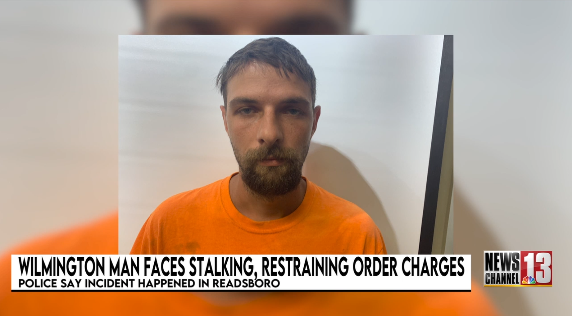 Man in orange shirt in police mugshot