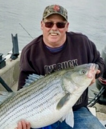 Man holding large striped bass on boat