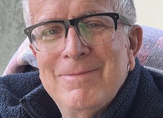 Older person wearing glasses smiling indoors