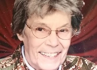 Smiling elderly woman with glasses and patterned jacket