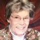 Smiling elderly woman with glasses and patterned jacket