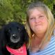 Woman posing with black dog wearing red bandana